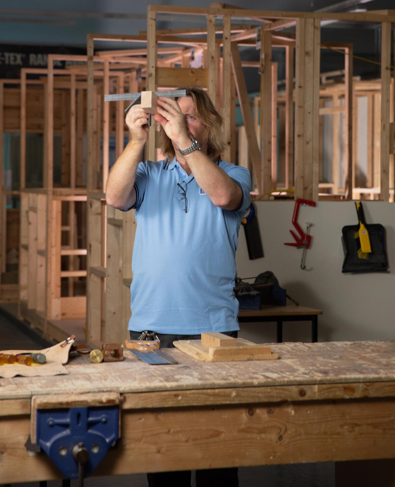 man measuring wood with square