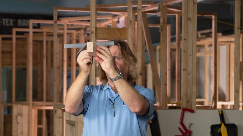 man measuring wood with square