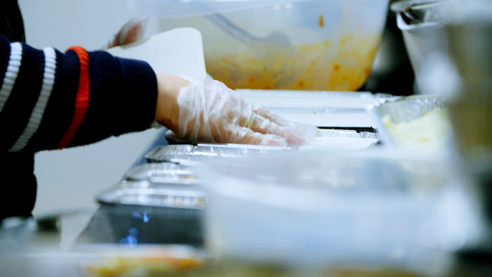 soup kitchen working putting lid on takeaway container
