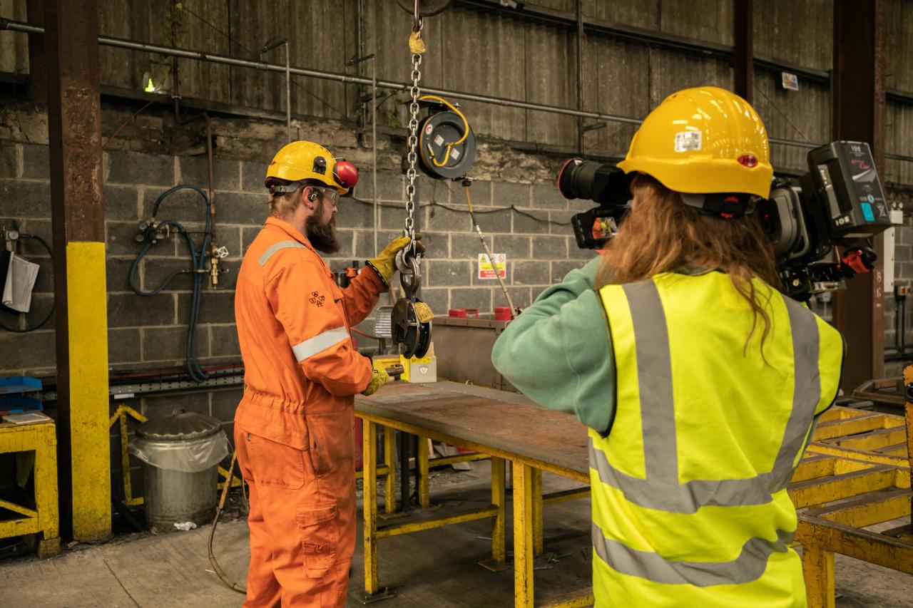 BM steel worker being filmed by camera operator