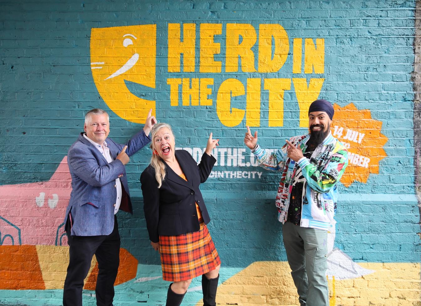 Sponsors of charity art trail pointing at branding 