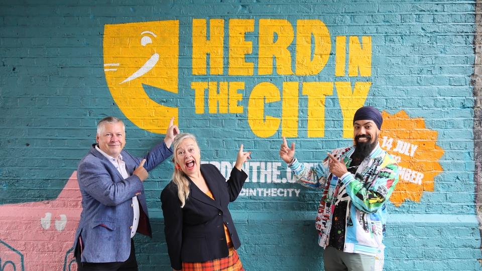 Sponsors of charity art trail pointing at branding