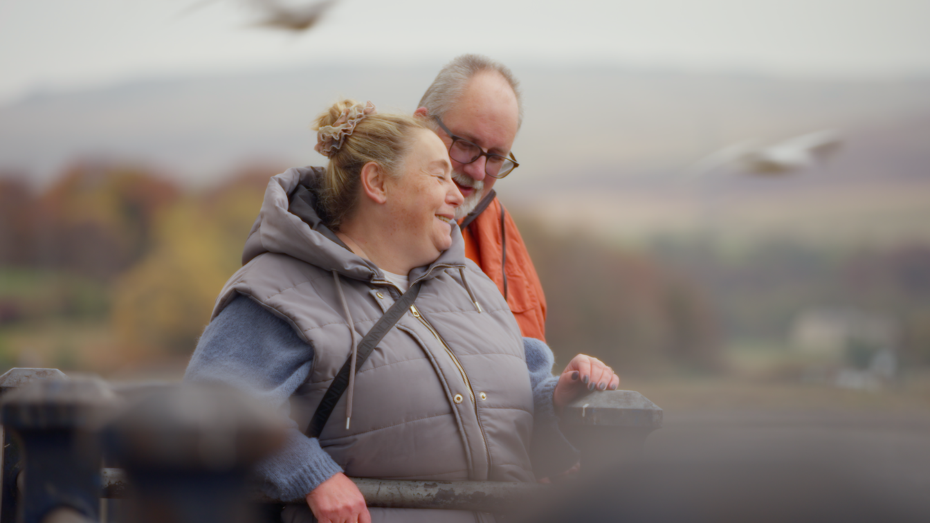 Foster carers together smiling at a lake