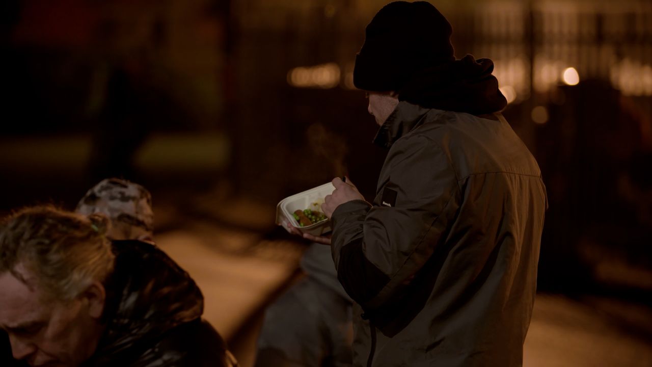 Man in hat and coat eating outside