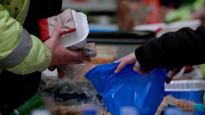 Person putting food into a blue bag