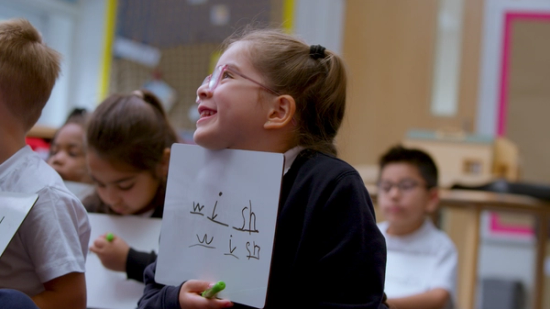 a child holding her whiteboard that has spelt wish