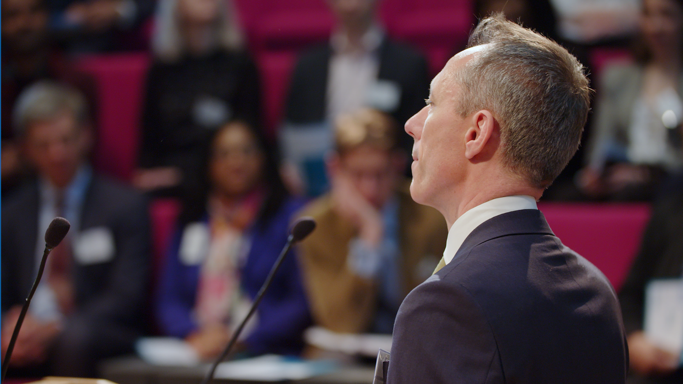 man delivering speech to audience for KPMG Reimagine Challenge