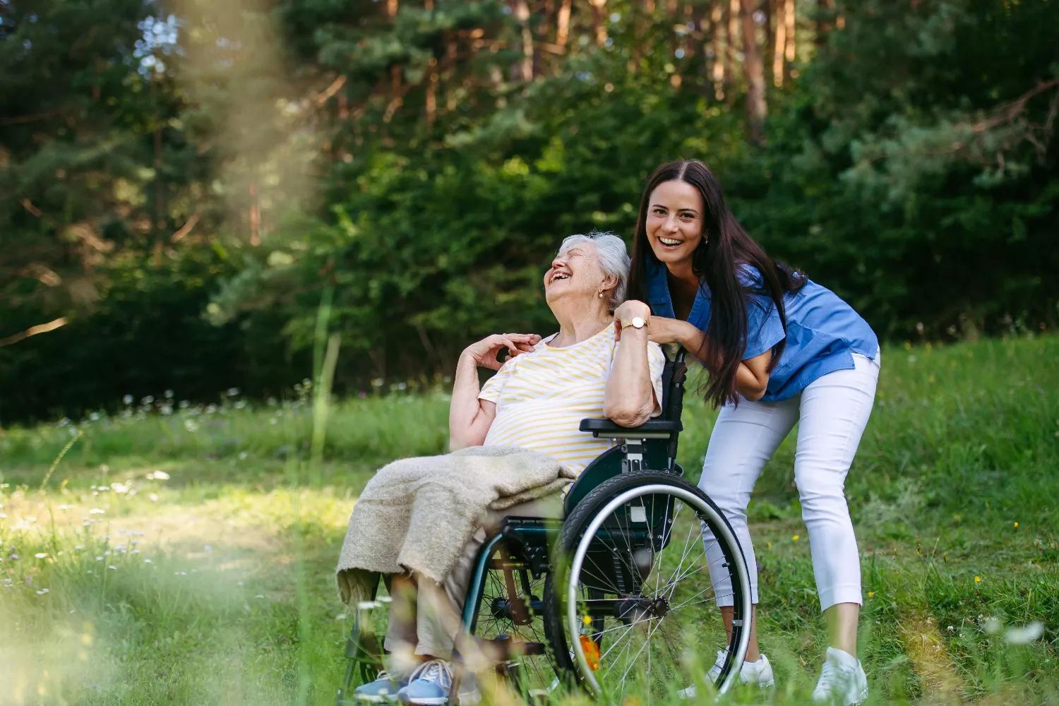 Wheelchair user enjoying a shaded summer outdoor setting with a caregiver