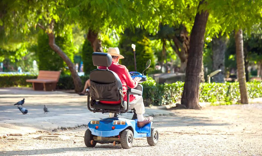 The old man wearing a hat is using a mobility scooter