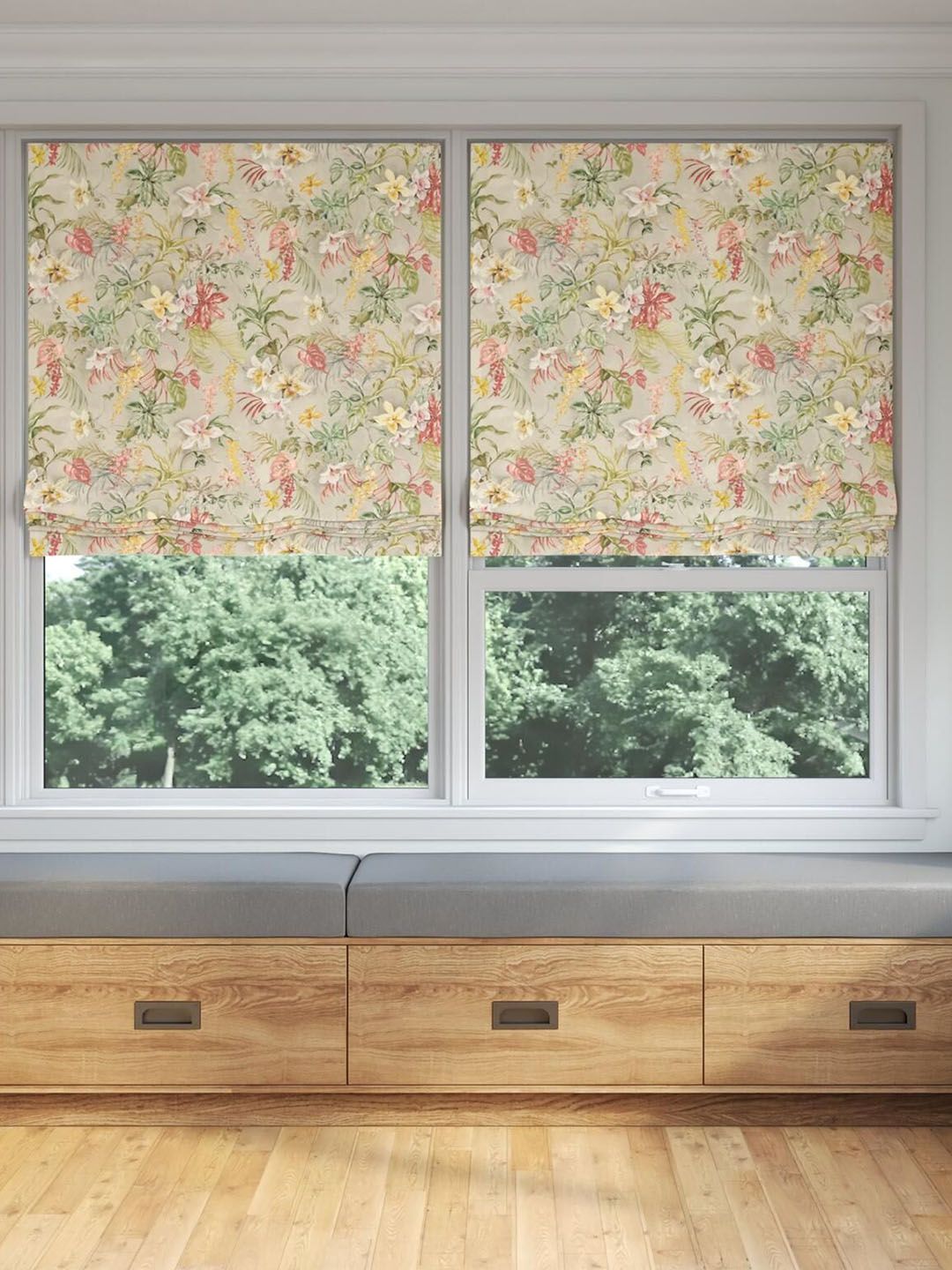 Floral printed Roman blinds by Acacia Fabric hang over a bay window in a living room