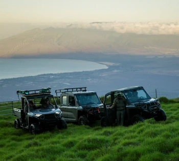 Utility vehicles parked at the top of Haleakala with west Maui mountains in the background