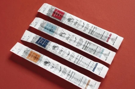 Four Maui Nui Venison stick flavors arranged on a red background — Original, Peppered, Peppered 10, and Spicy varieties shown side by side.