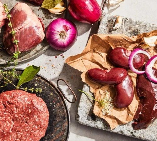 Maui Nui venison heart, kidneys, and liver plated side by side with red onions next to ground venison.