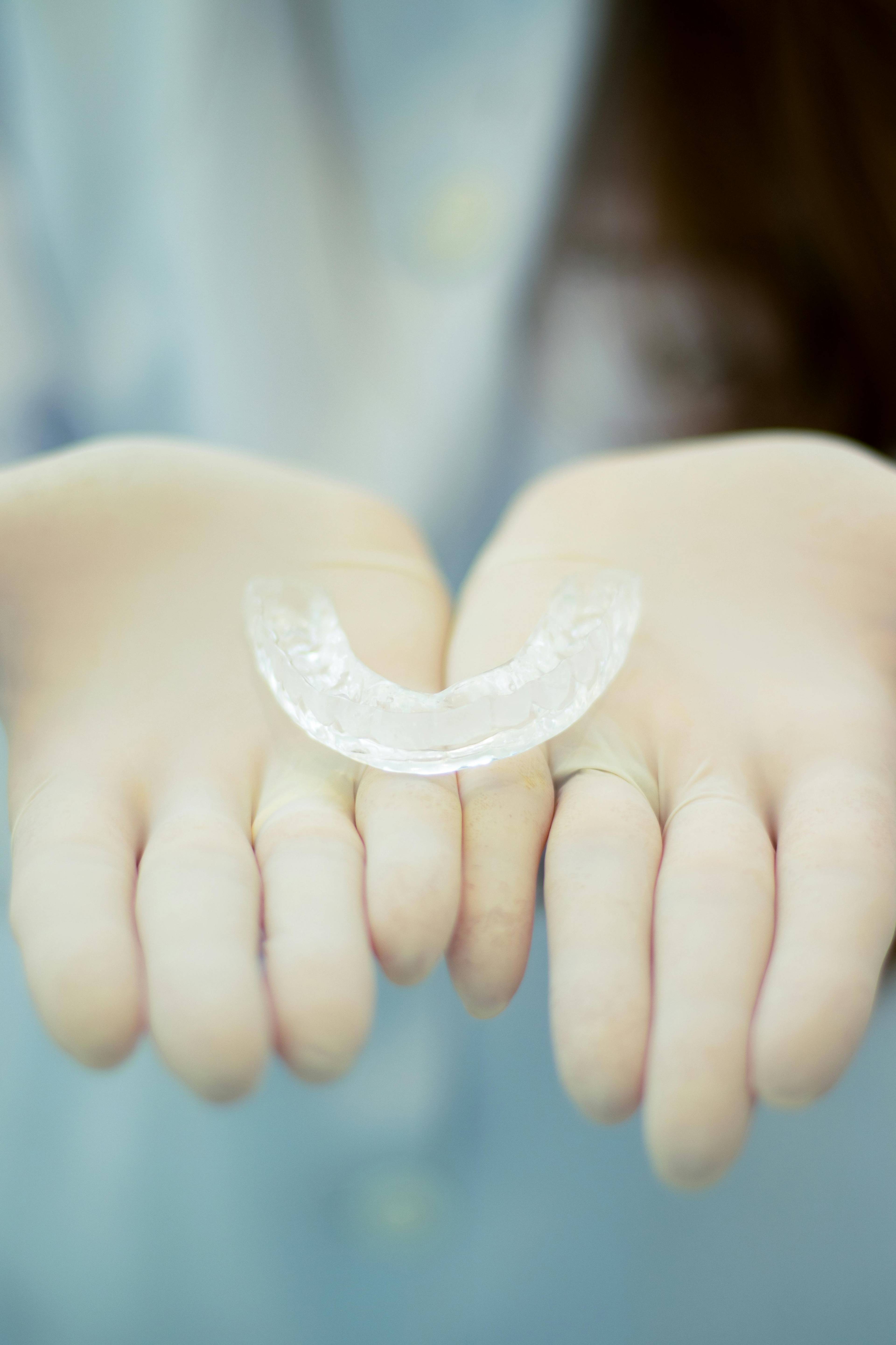 a dental mouthguard being held by a dentist with PPE on