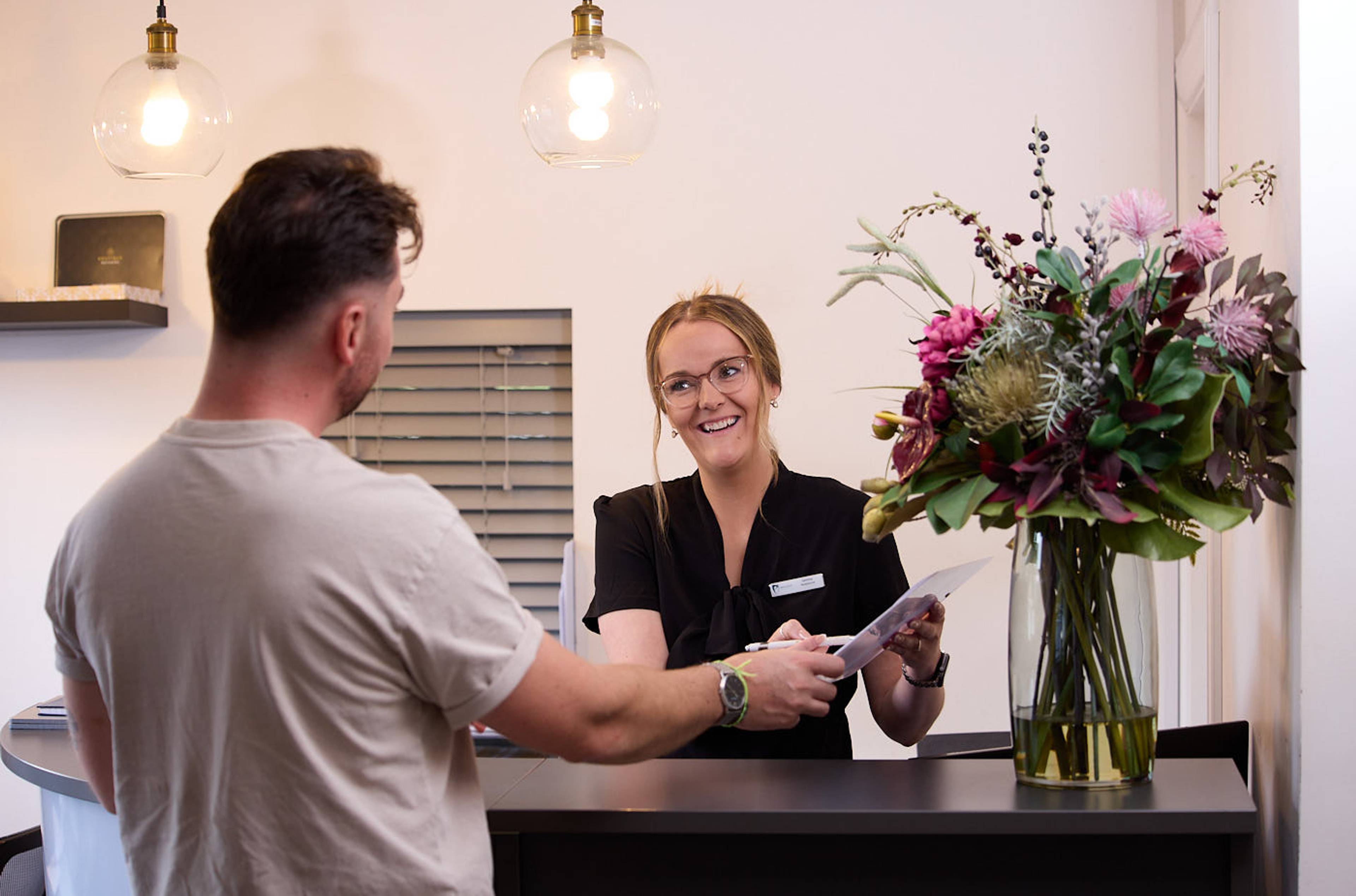 patient at reception signing medical forms in dental practice