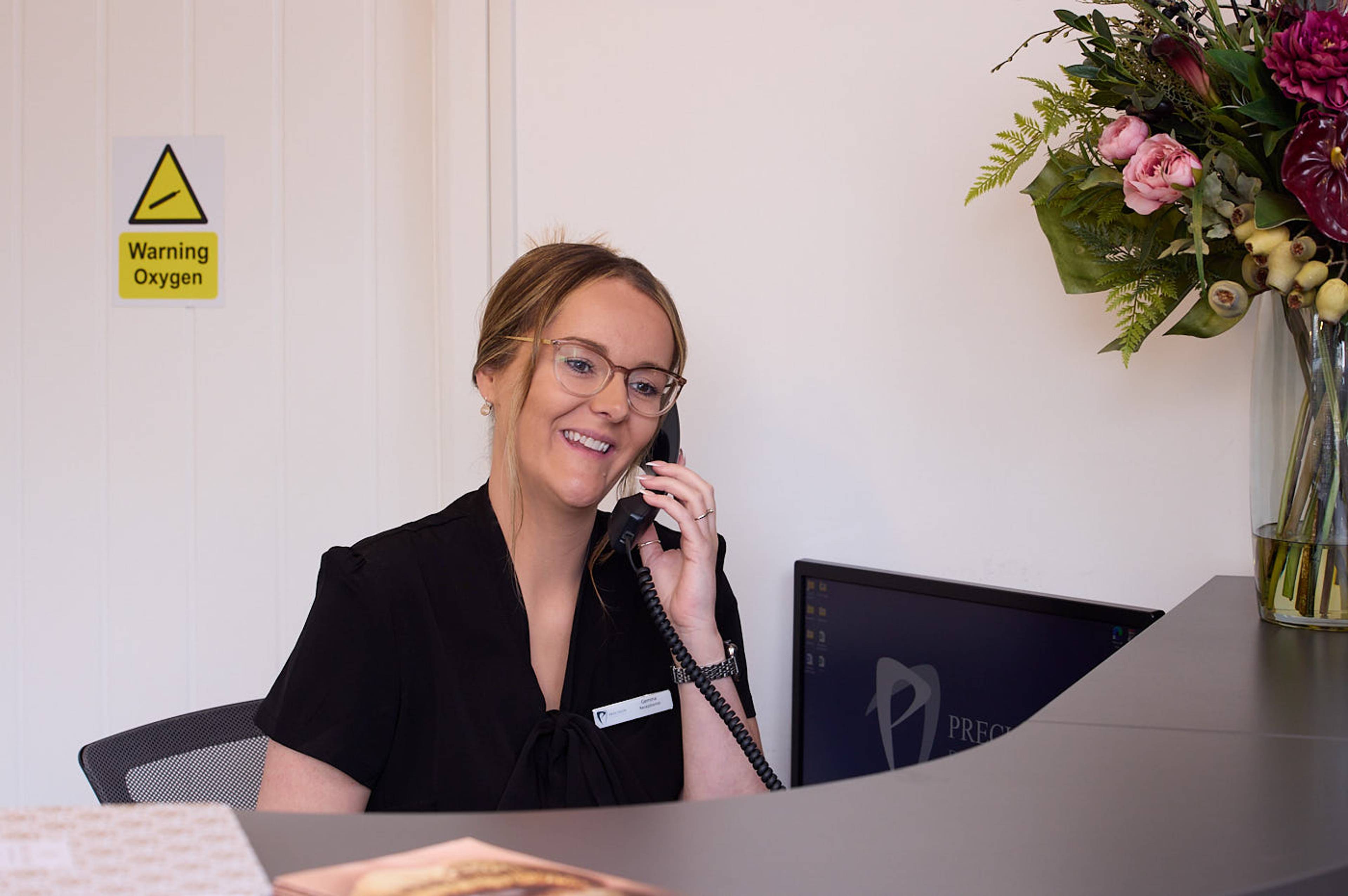 receptionist at dental practice taking calls from patients in Manchester