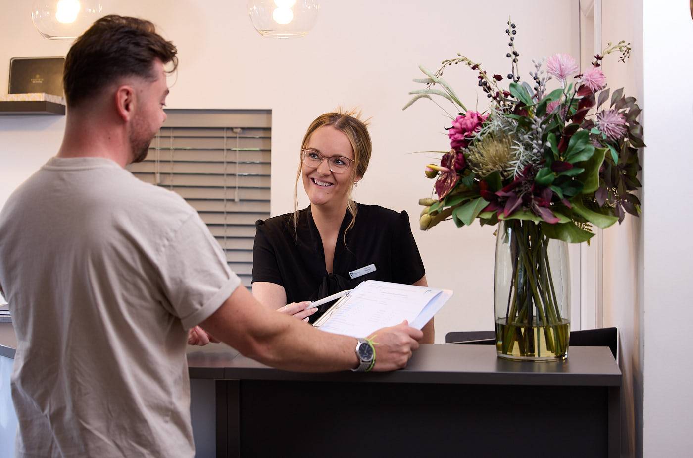 patient signing medical check forms at dental practice reception