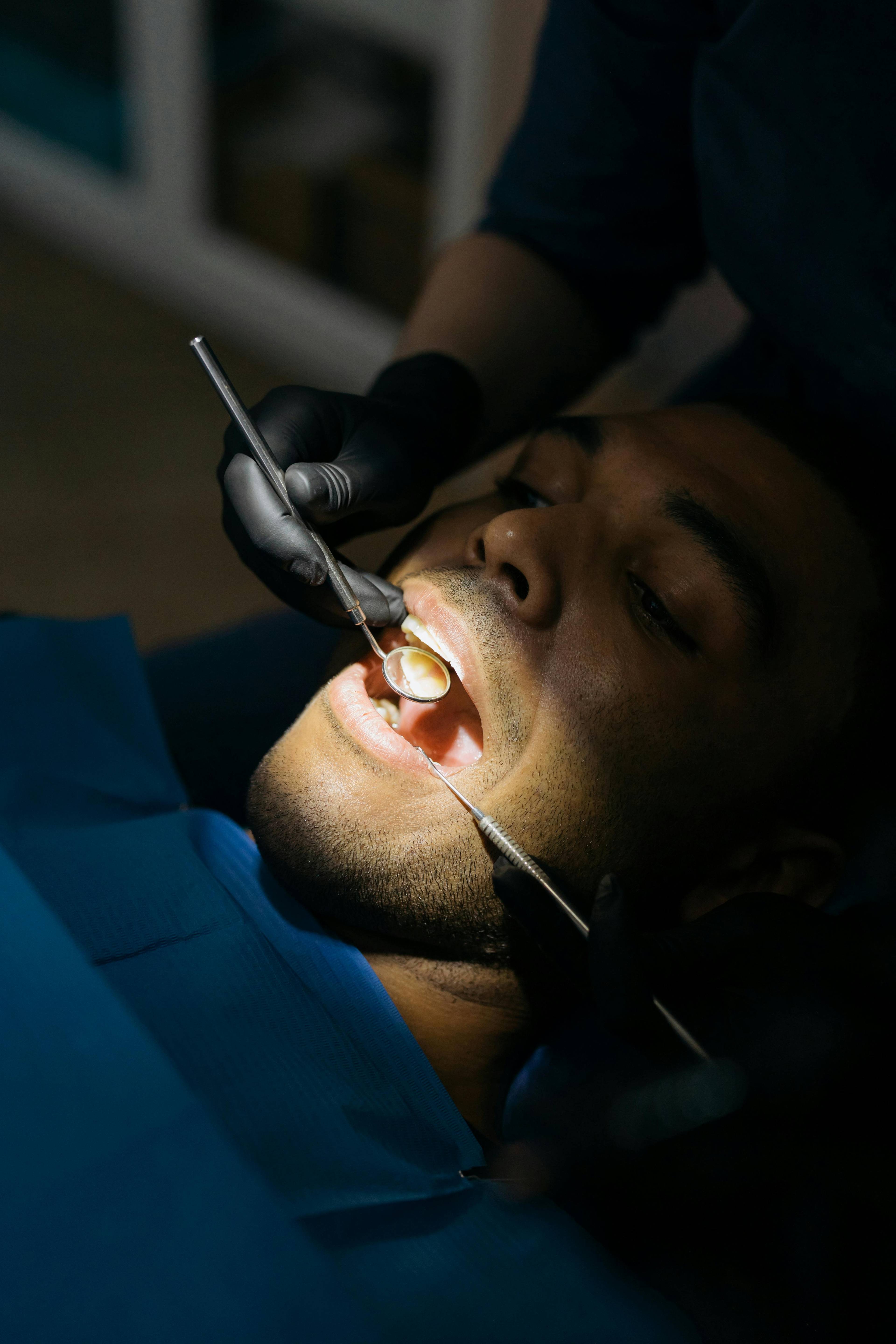 Patient having dental treatment with spot light on mouth area on dental instruments