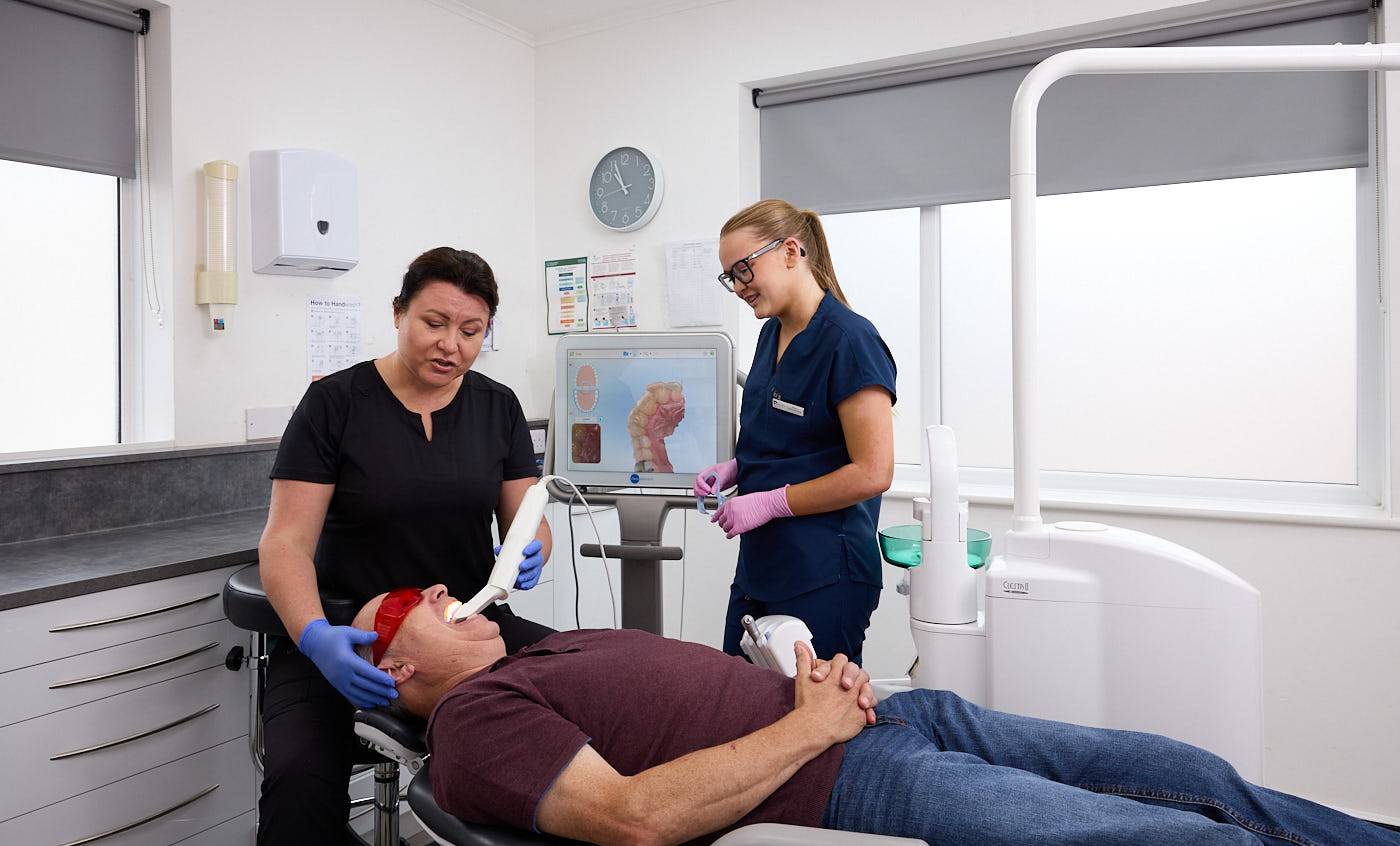patient having an intra oral scan with dentist and dental nurse in dental surgery
