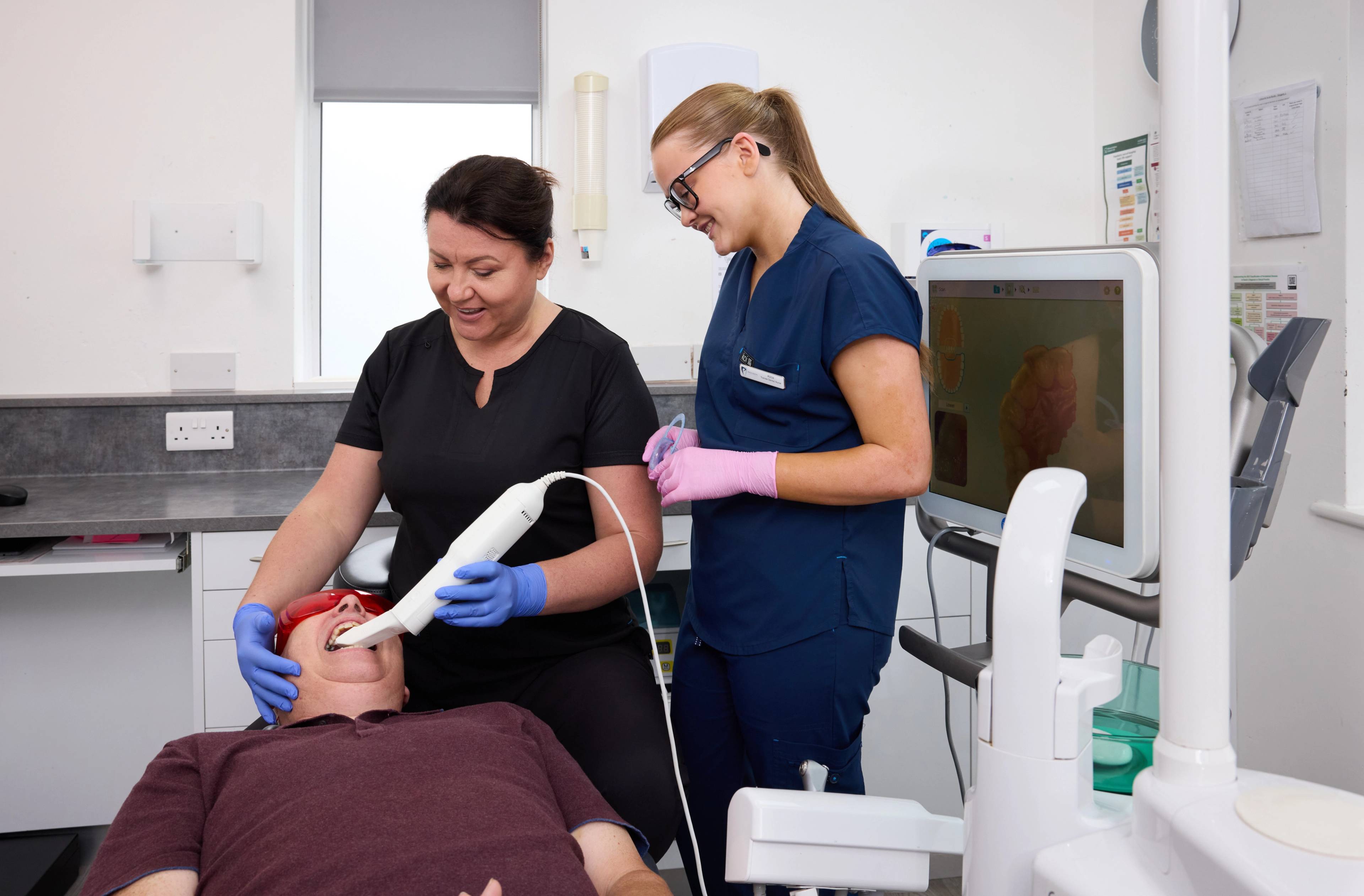 patient having an iTero scan for his whitening trays performed by a clinician and dental nurse helping