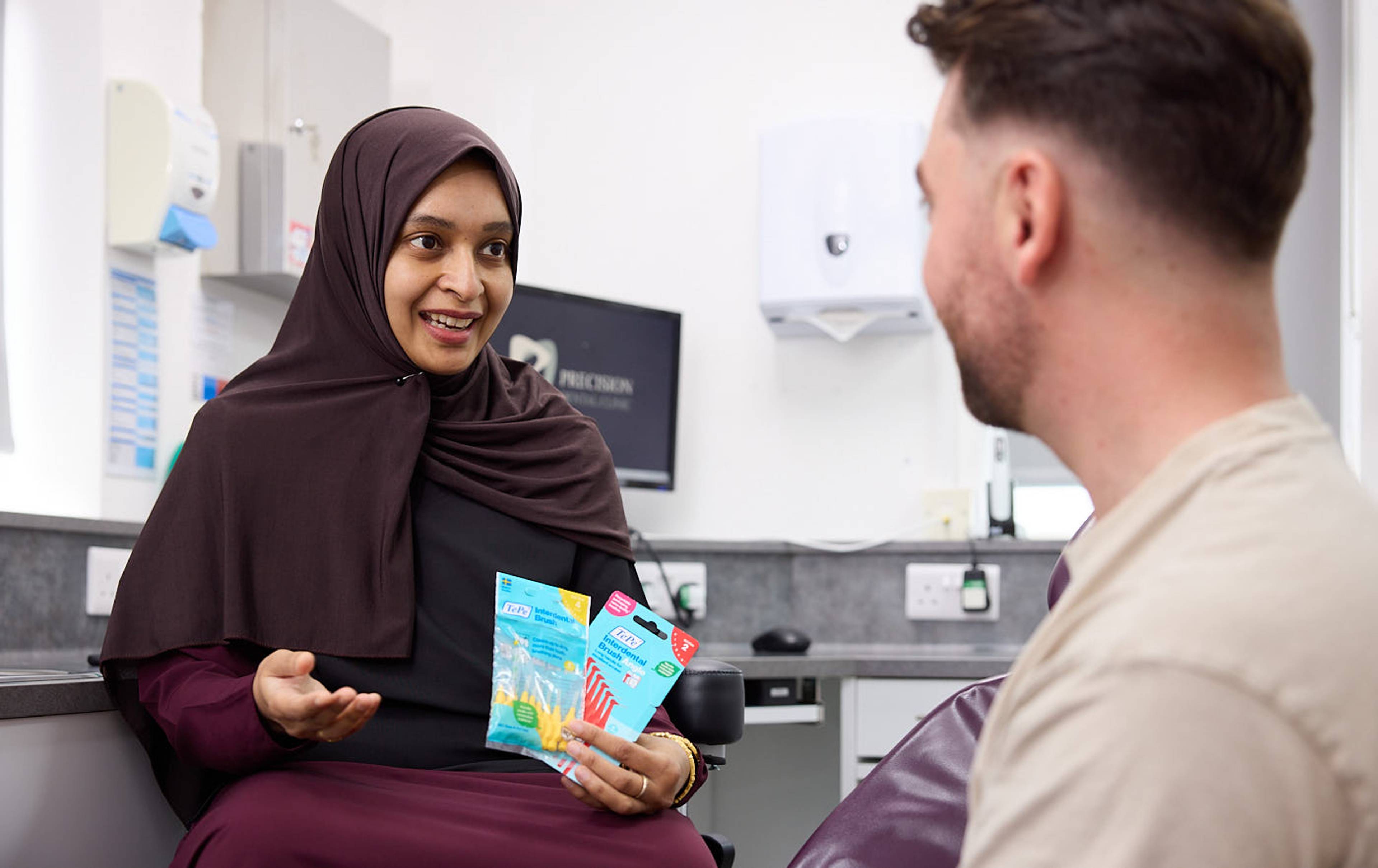 Dentist showing patient the importance of interdental brushes during a dental check-up