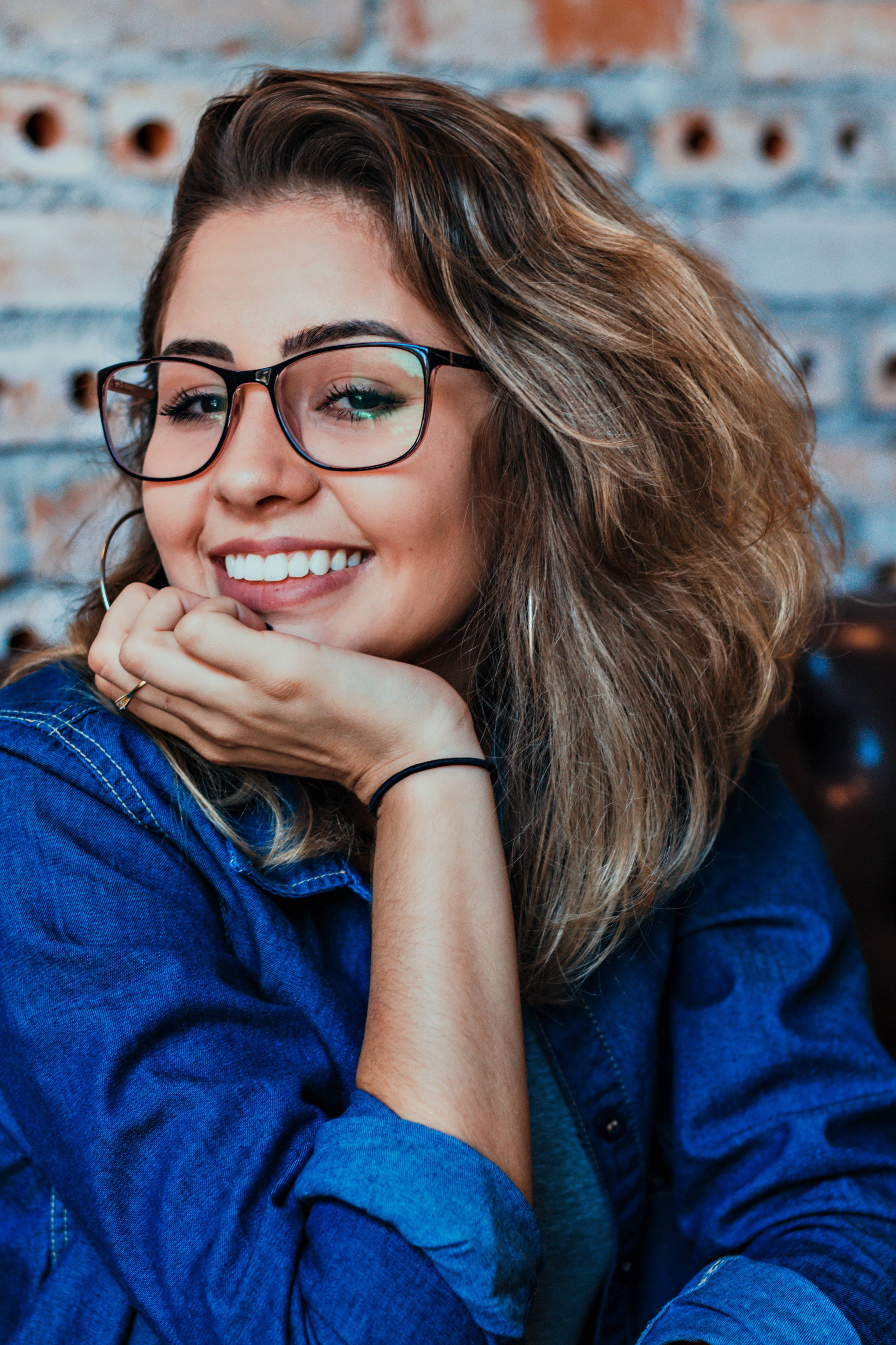 woman with glasses on smiling with whiter teeth at the camera