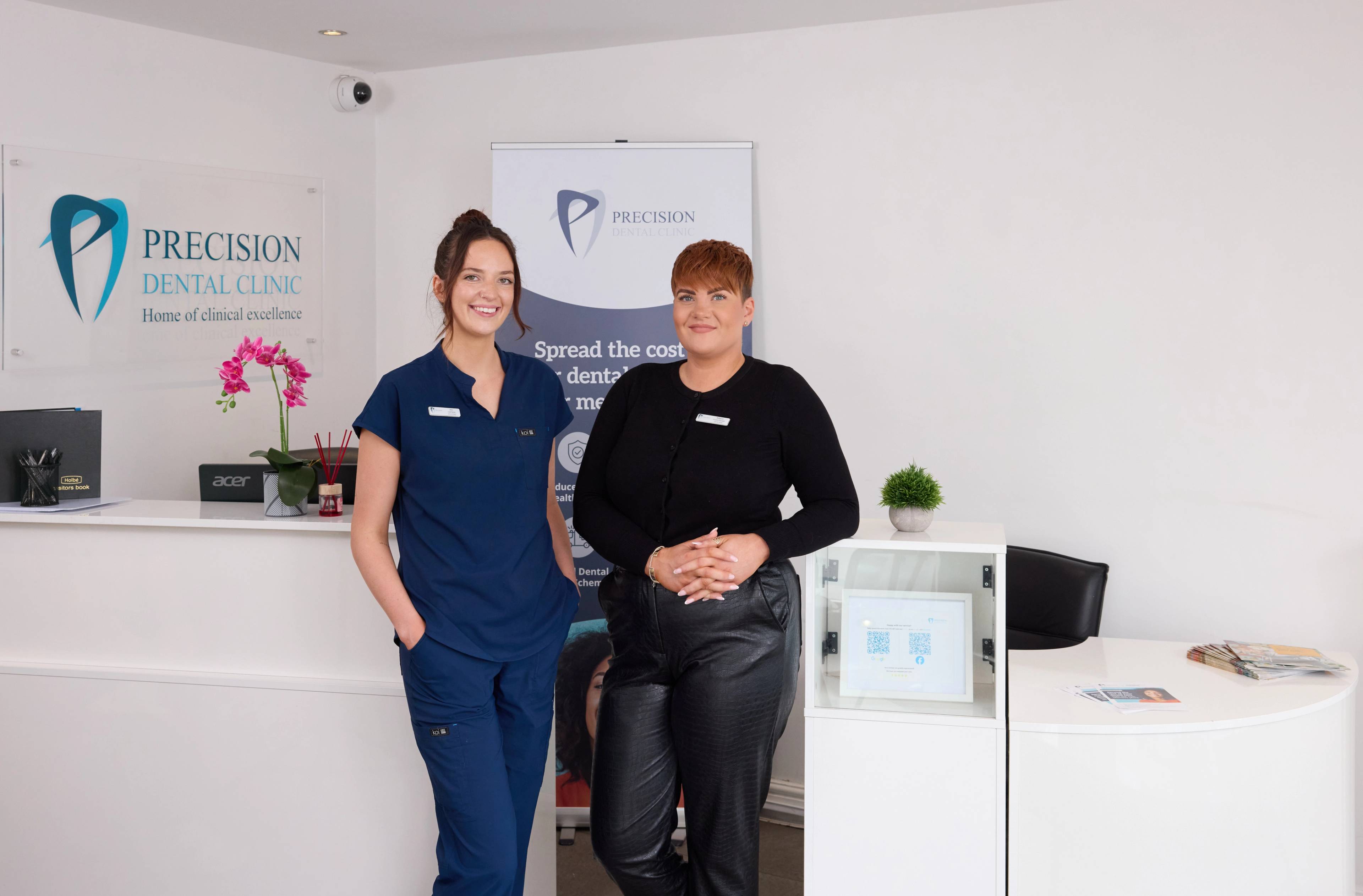Precision Dental Clinic Stockport team standing smiling in front of reception desk
