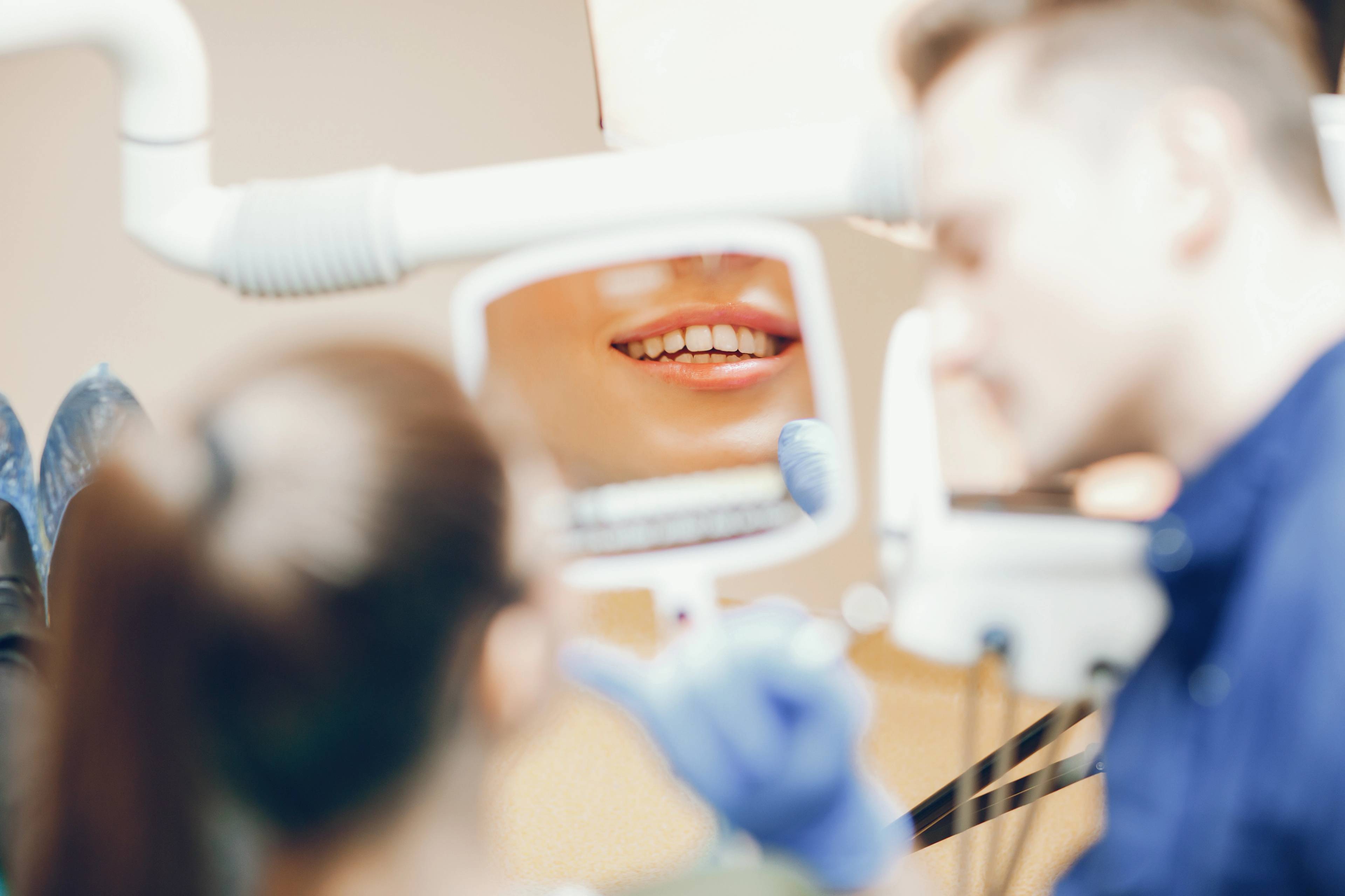 dentist holding up a mirror in a dental surgery for a patient to check out her smile makeover