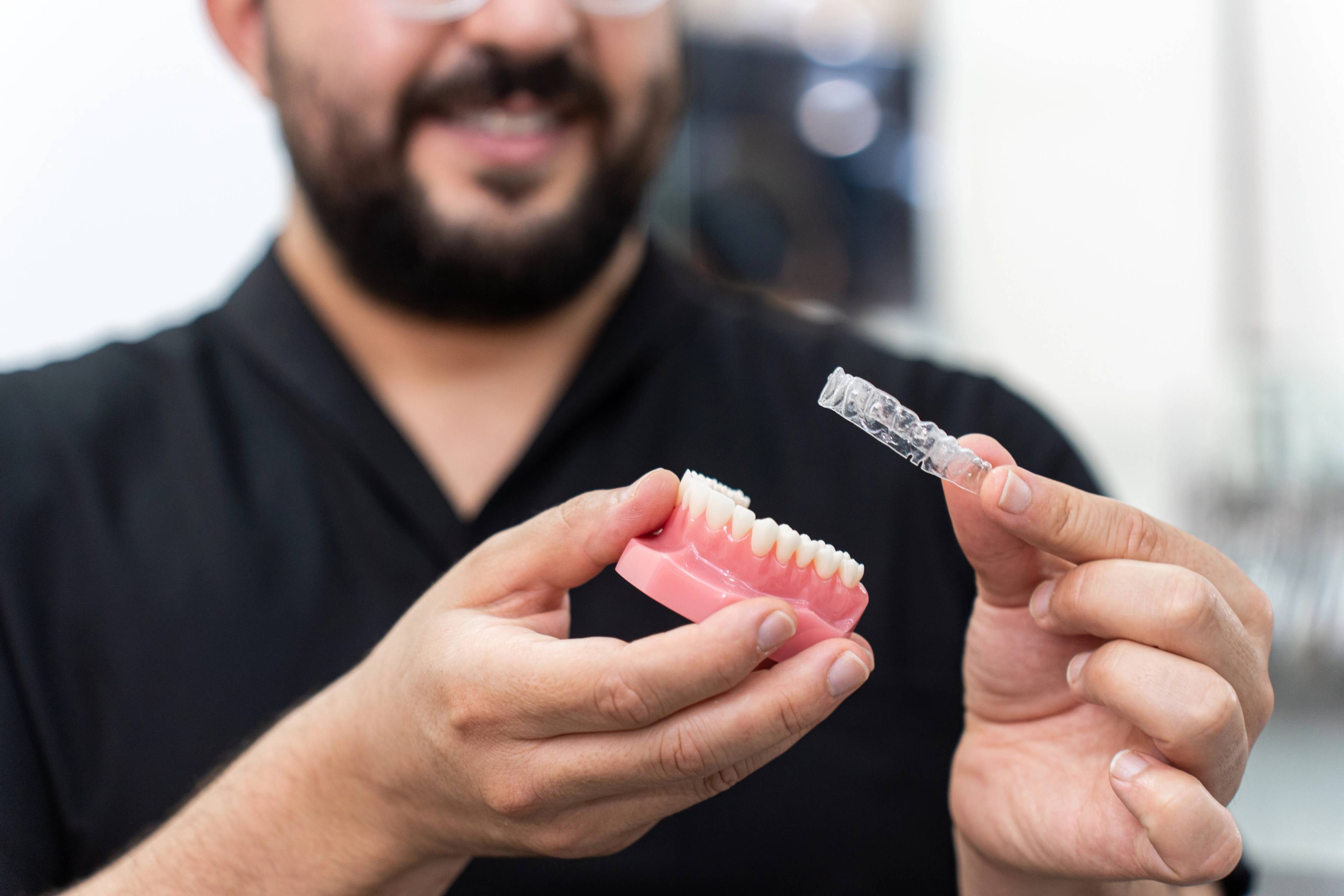 man holding Invisalign clear aligners in dental practice
