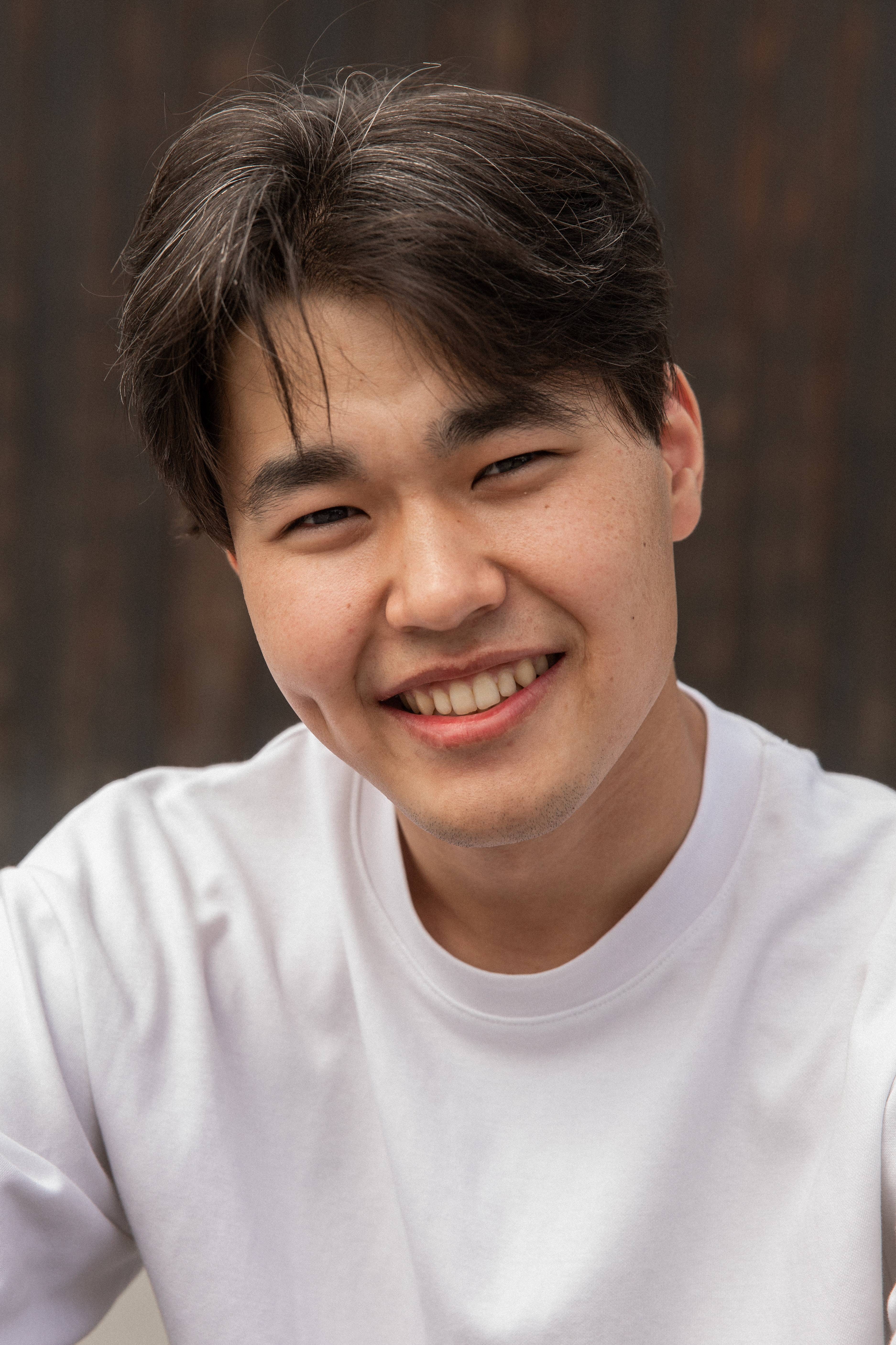 young Asian man smiling at the camera with bright aligned non-crooked teeth