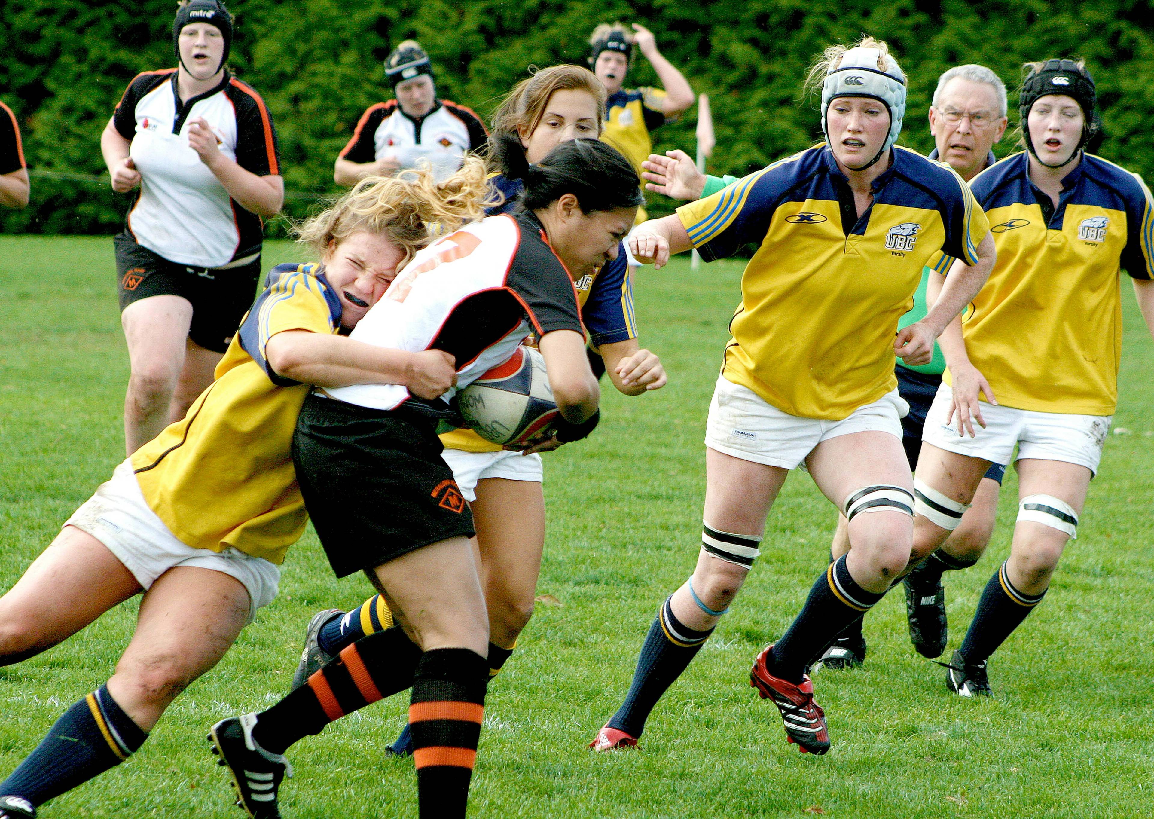 female rugby match with players wearing gum shields sport guards during contact tackle