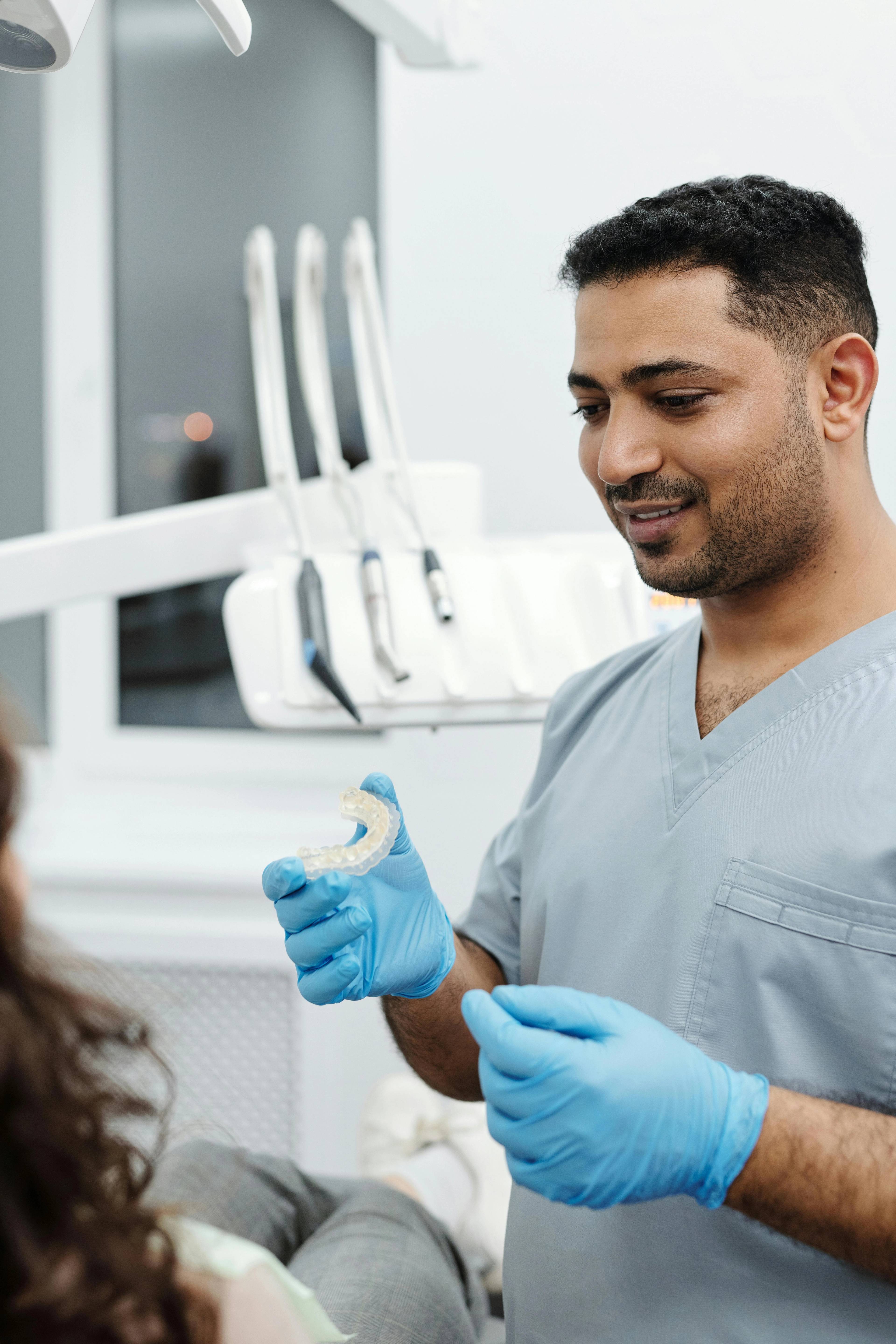 a dental mouthguard held by dentist showing patient how it can help with grinding pain