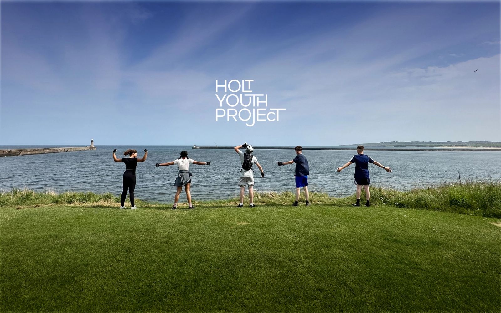 Young people standing at top of cliff with Holt Youth Project logo overlaying