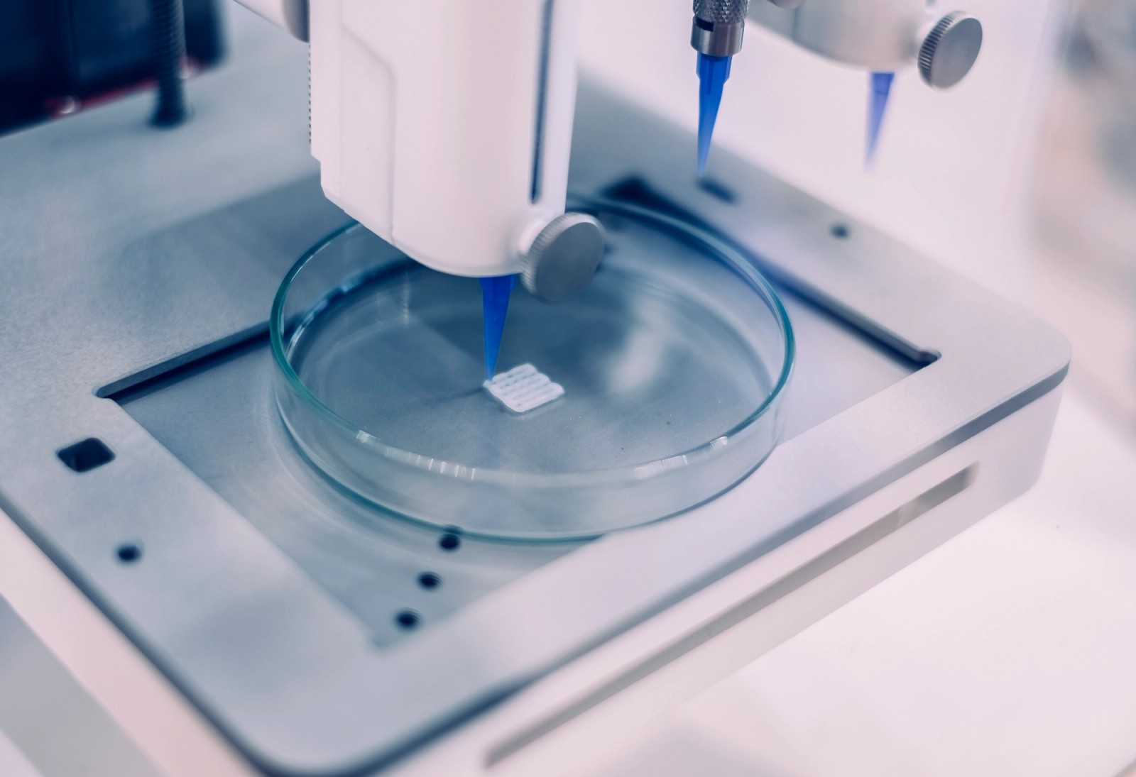 A bioprinter nozzle depositing a square hydrogel construct