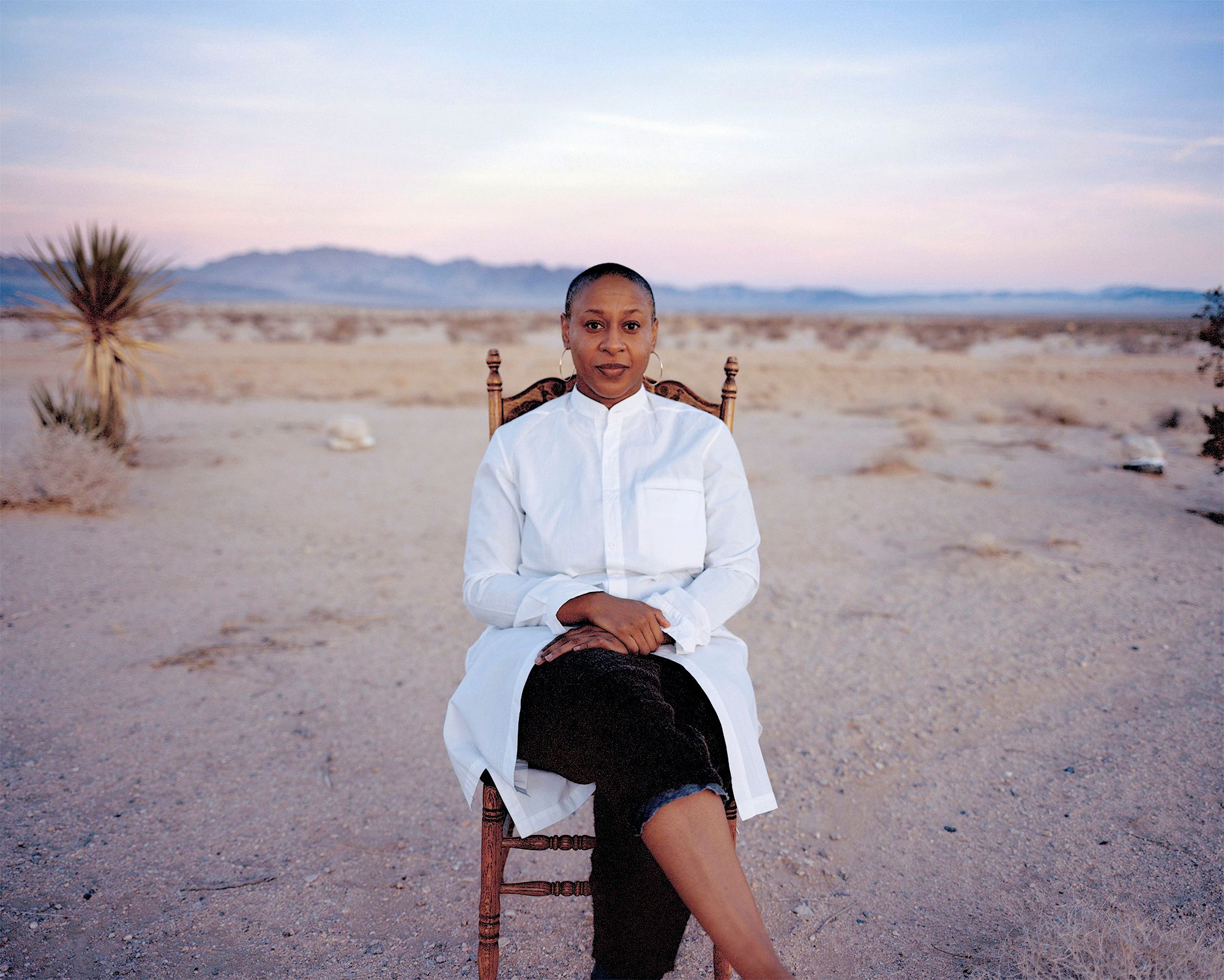 Jennifer Harge seated in a wooden chair with desert surroundings