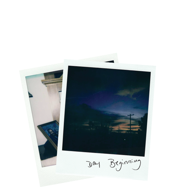 Two stacked Polaroid photographs, the top of a sky at dawn with a handwritten note which says "Day Beginning"