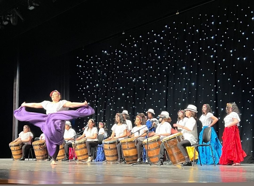 dancer onstage with a row of drummers behind them