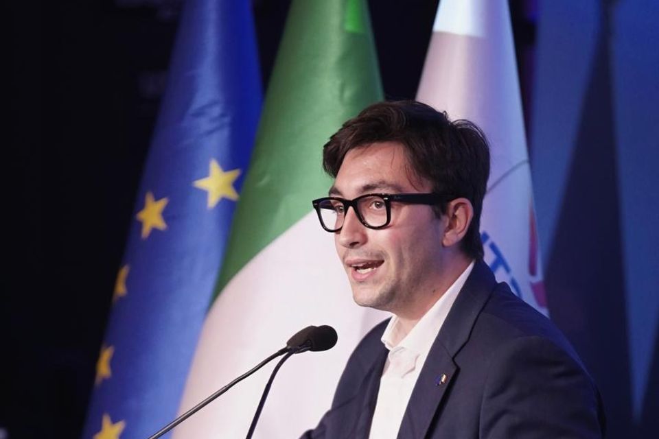Leonardo Gallozzi parla dal palco davanti alle bandiere italiana ed europea