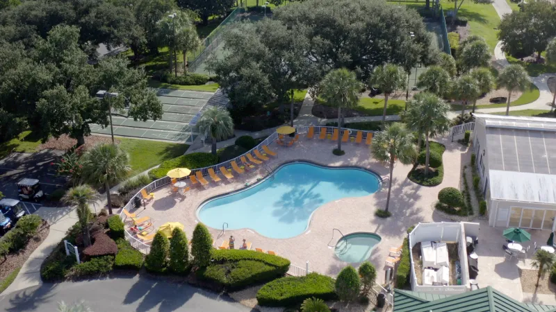 An aerial view of a pool with lounger around the edges, outside of the community clubhouse.