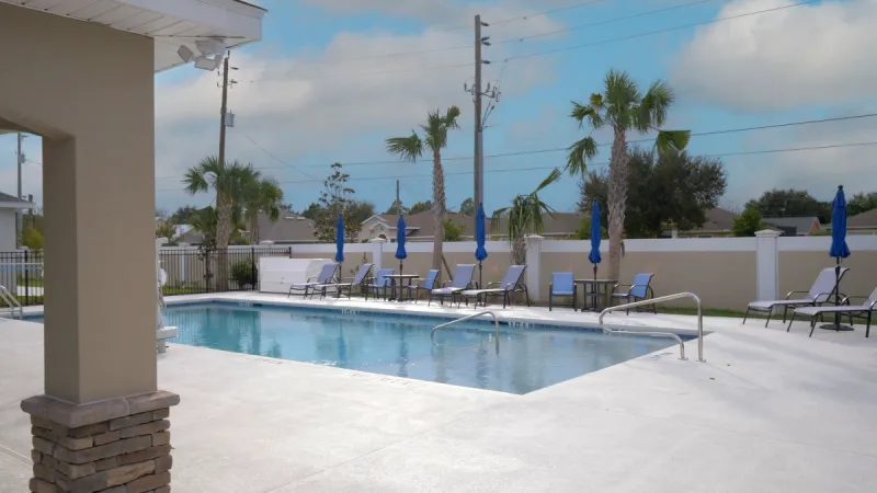 The sparkling blue Matanzas Lakes pool with clear water surrounded by lounge chairs and palm trees.