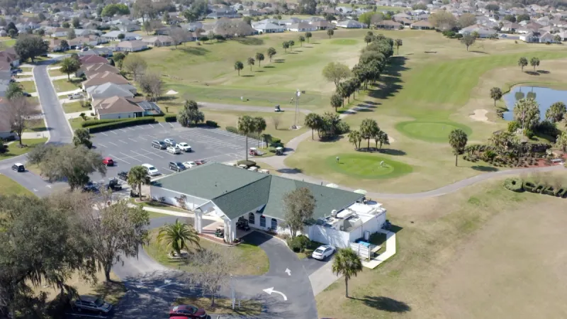 Aerial view of clubhouse surrounded by golf greens.