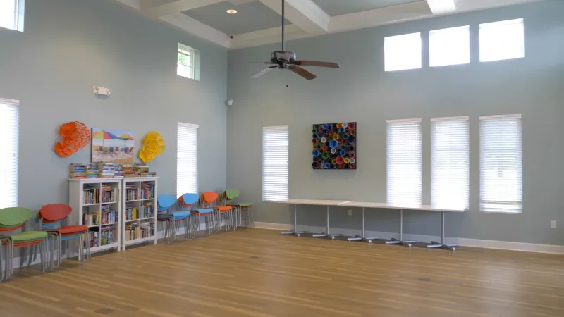 A bright an airy activity room at the Lakes at Harmony with colorful chairs, bookshelves, and artwork on the walls.