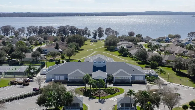 A contemporary style clubhouse with homes surrounding, all overlooking the sparkling water.