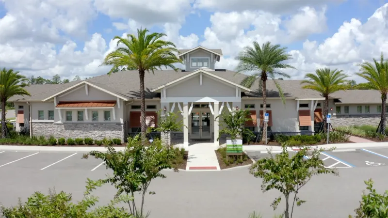 Palms at Serenoa clubhouse entrance surrounded by parking and palm trees.