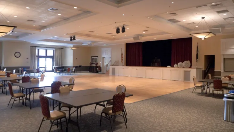 Stone Creek ballroom with tables and chairs arranged around a wood dance floor and performance stage.