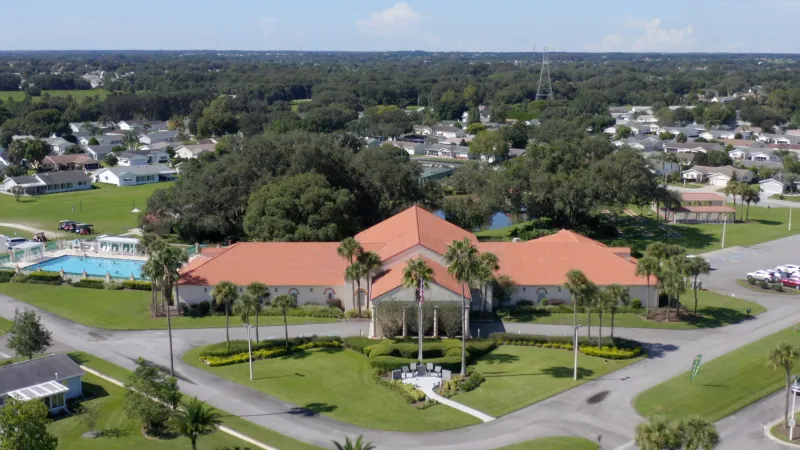 Aerial view of Spruce Creek South with a central clubhouse, pool, and homes amidst lush greenery.