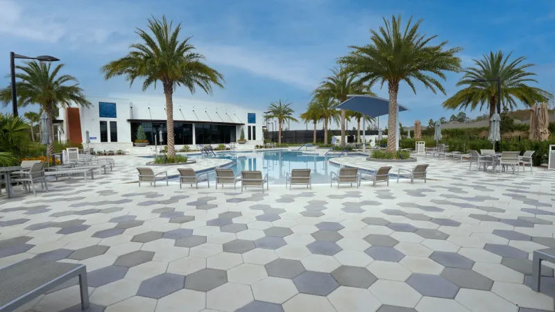 A spacious pool deck with loungers leading to a modern clubhouse at Del Webb eTown.