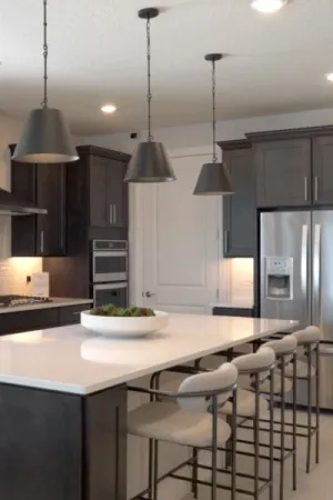A modern kitchen island with sleek dark cabinets, overhead pendant lights, and stainless steel appliances including a refrigerator, oven, and microwave.