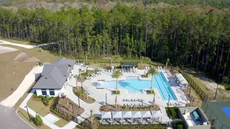 Stillwater by Lennar's sparkling pool and pool house surrounded by lounge chairs.