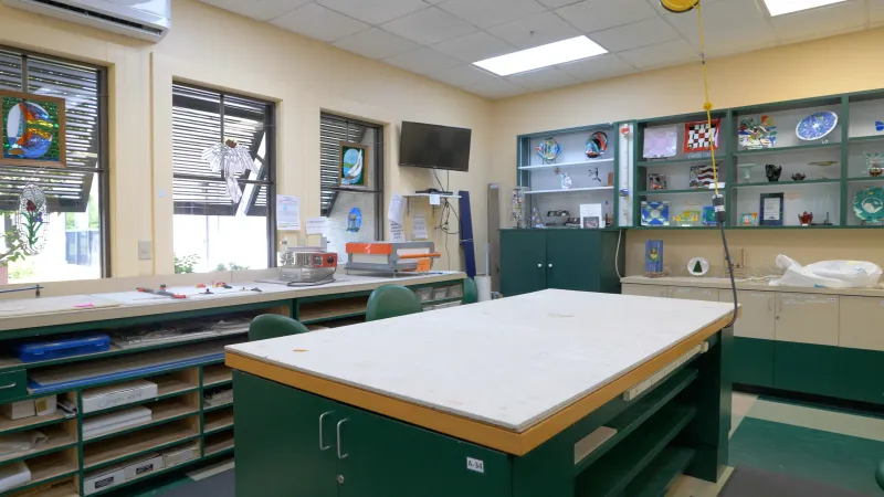 A cozy craft room in Sun City Center, featuring a green craft island, well-stocked craft supplies, and bright lighting to facilitate various creative projects.